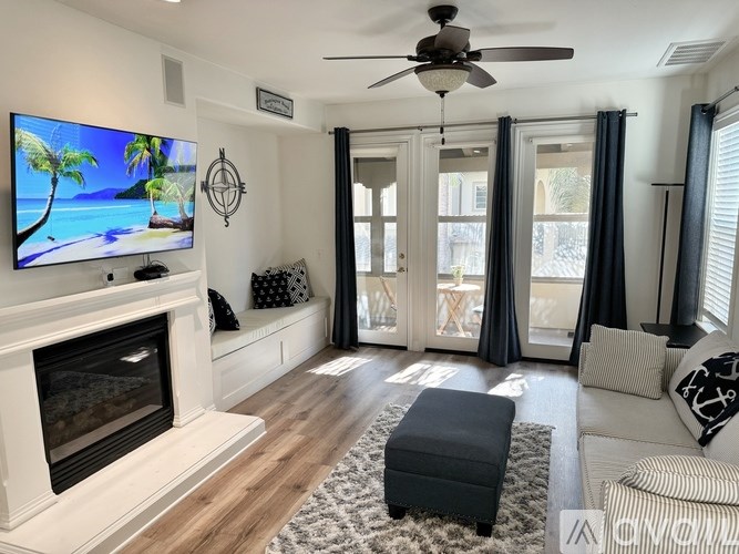 A living room with a fireplace and a flat screen TV mounted above it.