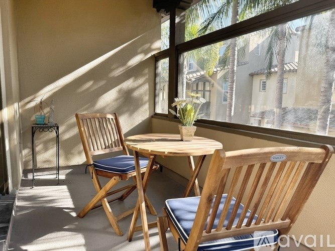 Two chairs and a table are on a patio with a view of a street.
