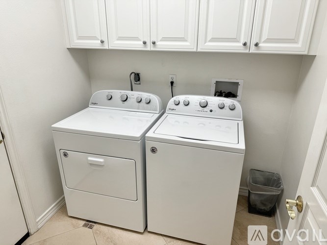 Two white front loading washing machines in a laundry room.