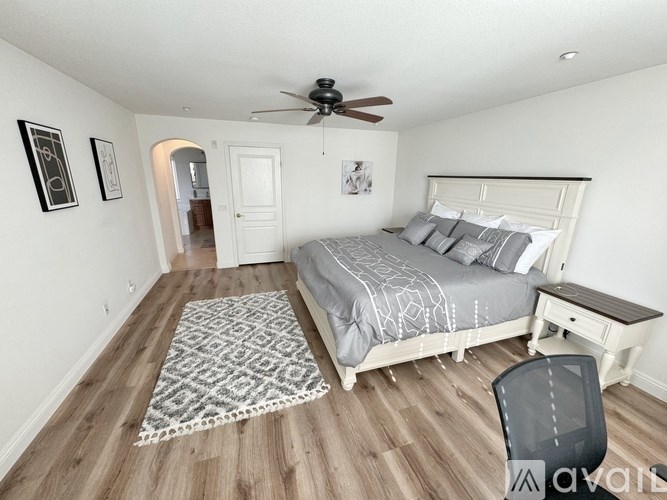 A bedroom with a bed, chair, and ceiling fan.