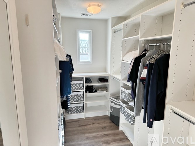 A white closet with clothes hanging and drawers underneath.