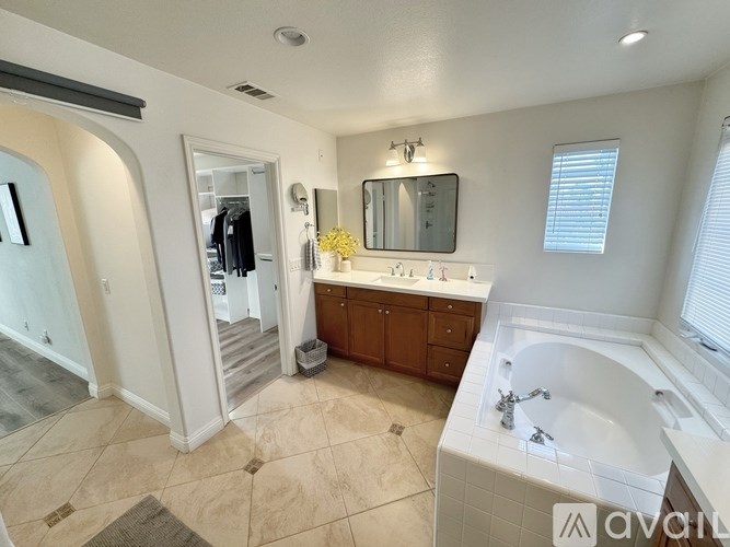 A bathroom with a tub, sink, mirror, and a window.