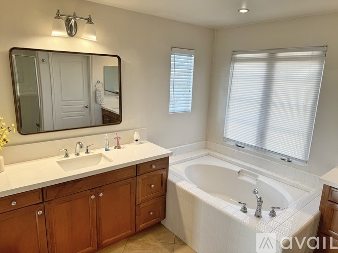 A bathroom with a white tub, sink, and mirror.