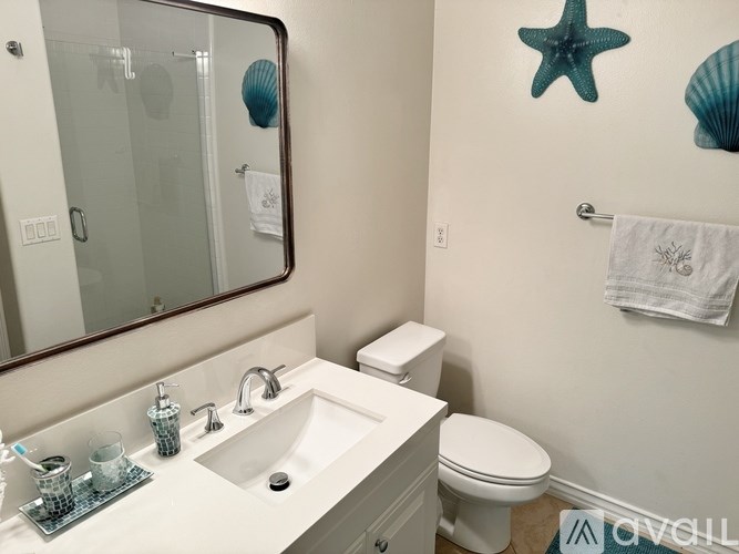 A bathroom with a white toilet, sink, and a starfish decoration on the wall.