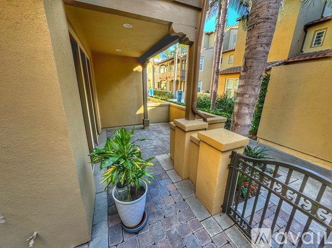 A patio with a potted plant and a gate.