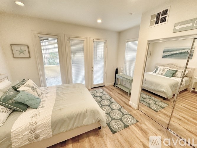 A bedroom with a large bed and a mirrored closet door.