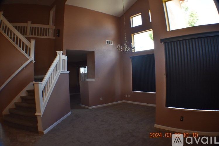 A living room with a staircase and a chandelier.