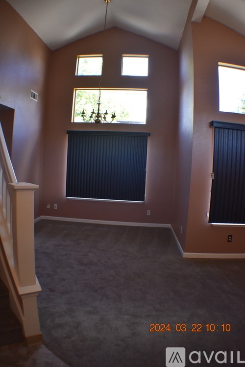 A room with a carpeted floor and a window with blinds.