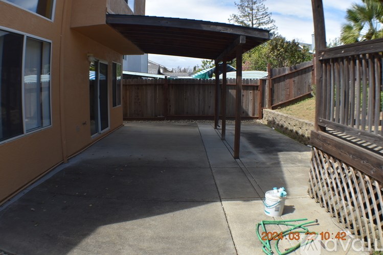 A patio area with a wooden fence and a building with a brown exterior.