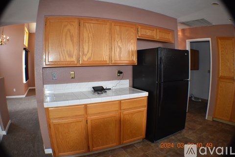 A kitchen with wooden cabinets and a black refrigerator.