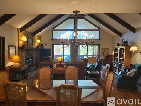 A living room with a glass table and chairs, a fireplace, and a chandelier.