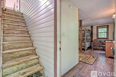 A wooden staircase leads to a living room with a couch and a rug.