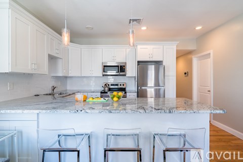 A kitchen with white cabinets and a marble countertop.