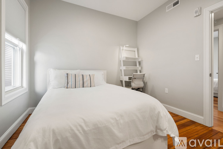 A bedroom with a white bed and a wooden floor.