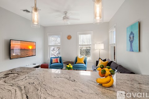 A living room with a grey carpet and a painting on the wall.