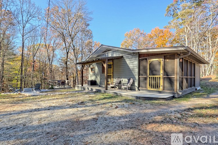 A house with a porch and a covered patio is surrounded by trees.