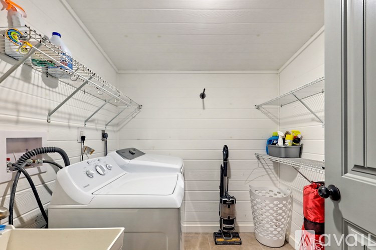 A white laundry room with a washer and dryer, a mop, and a broom.