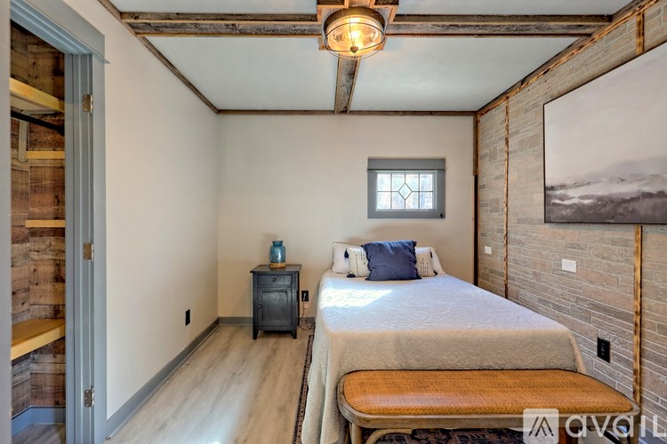 A bedroom with a bed, nightstand, and window.