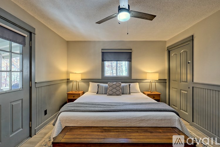 A bedroom with a bed, two lamps, and a ceiling fan.