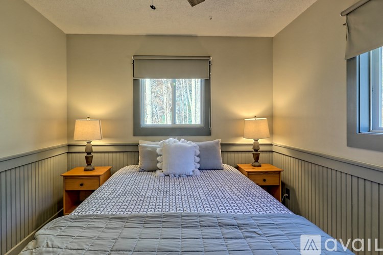 A bedroom with a bed, two lamps, and a window with a view of trees outside.