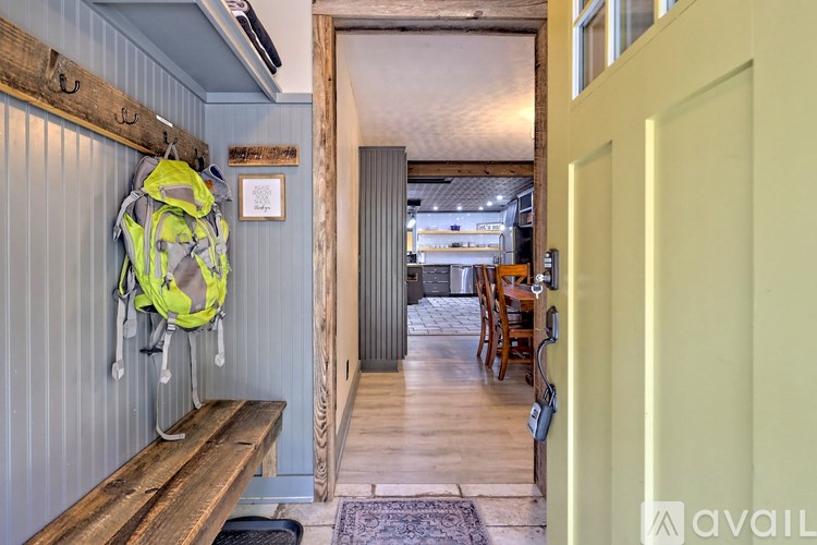 A green backpack hangs on a blue wall next to a wooden bench.