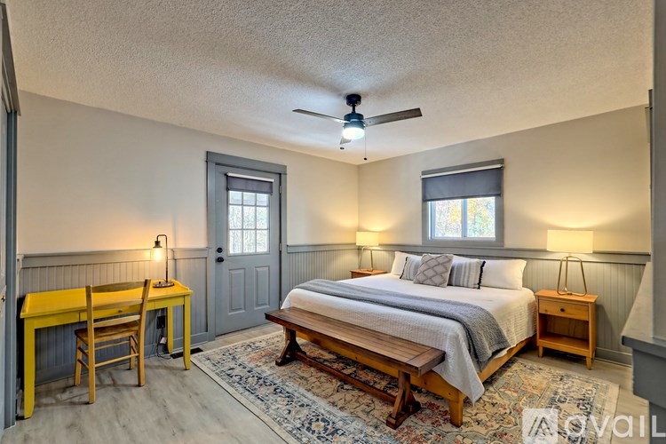 A bedroom with a bed, desk, and window.