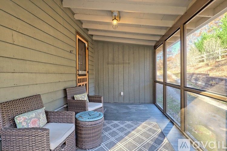 A sunroom with a wicker chair and ottoman.