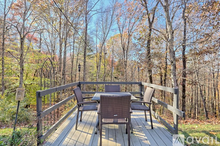 A wooden deck with a table and chairs overlooks a forest.