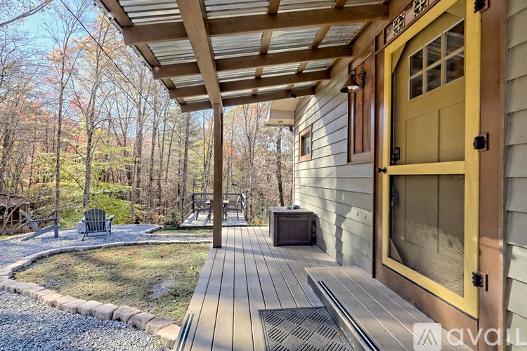 A wooden deck with a yellow door and a bench under a roof.
