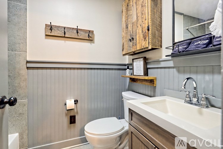 A bathroom with a toilet, sink, and wooden cabinet.