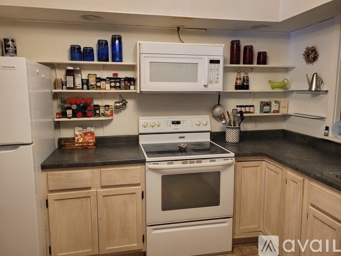 A kitchen with a white fridge, white microwave, white oven and white cabinets.