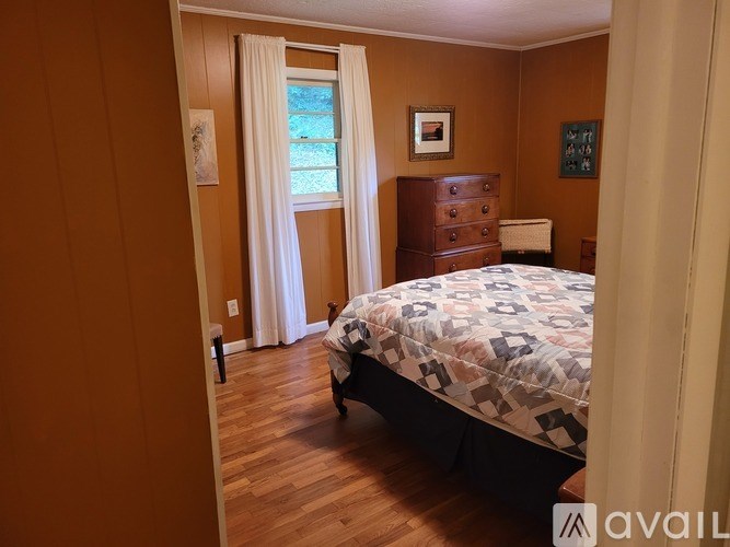 A bedroom with a bed, dresser, and window.