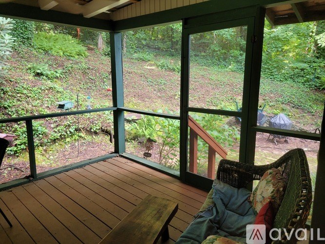 A screened porch with a view of the forest.