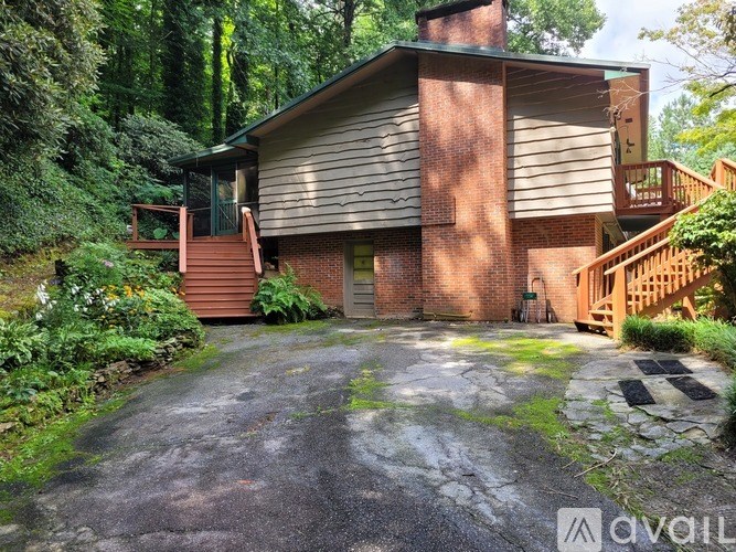 A house with a red brick chimney and a balcony is surrounded by greenery.