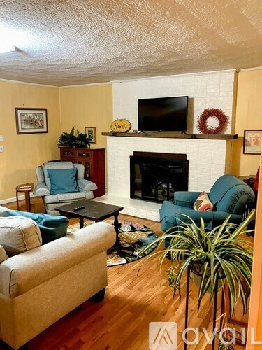 A living room with a fireplace and a TV on the wall.