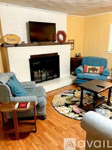 A living room with a fireplace and a TV on the wall.