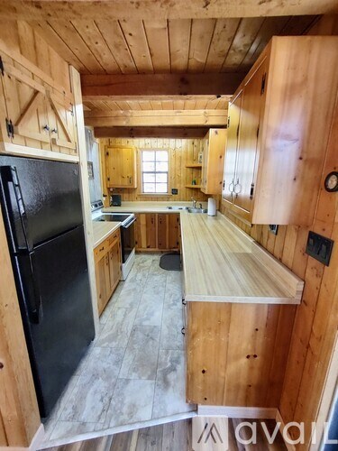 A kitchen with wooden cabinets and a black refrigerator.