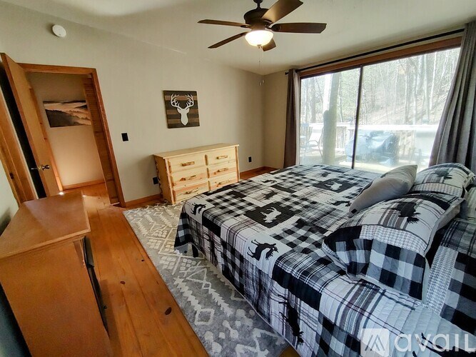 A bedroom with a bed, dresser, and a ceiling fan.