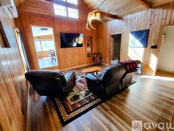 A living room with a black couch and wooden walls.