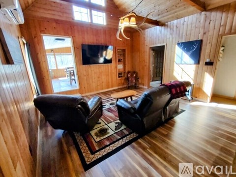 A living room with a black couch and wooden walls.