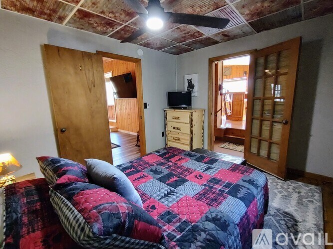 A bedroom with a bed, dresser, and ceiling fan.