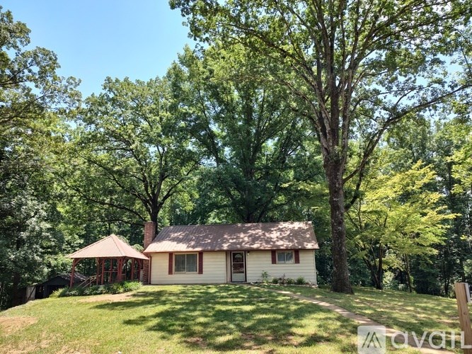 A house with a brown roof is surrounded by trees.