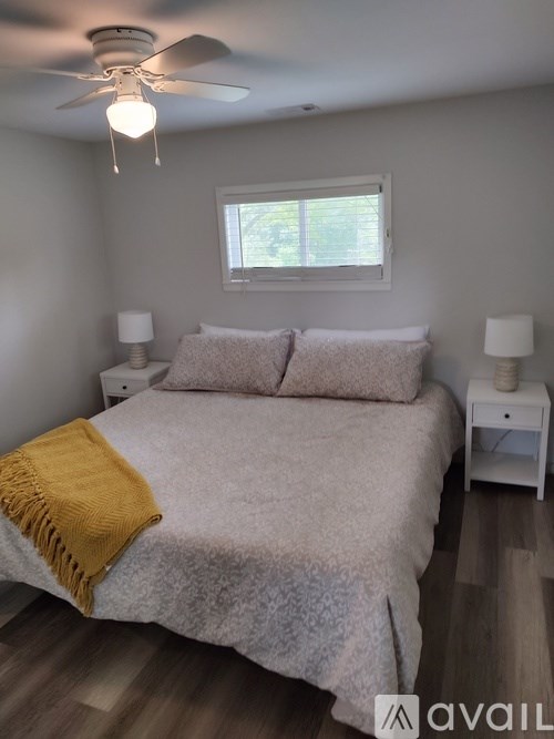 A bedroom with a bed, two lamps, and a ceiling fan.