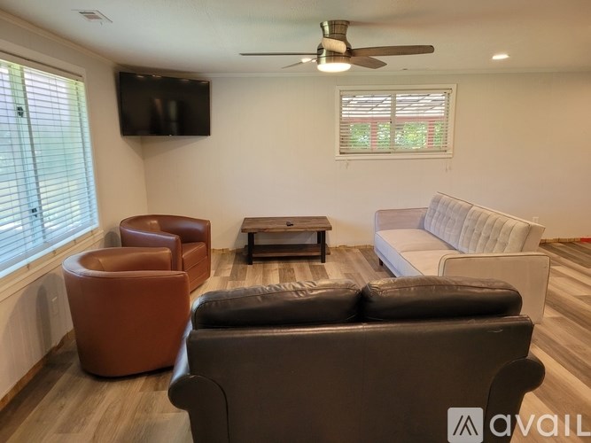A living room with a brown leather couch, a white sofa, and a television mounted on the wall.