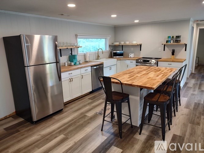 A kitchen with a wooden table and chairs, a refrigerator, and a stove top oven.