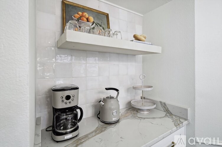 A coffee machine and a kettle are on a marble countertop.