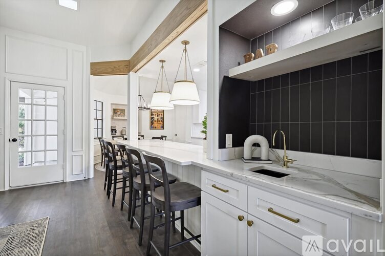 A kitchen with white cabinets and black tiles on the backsplash.