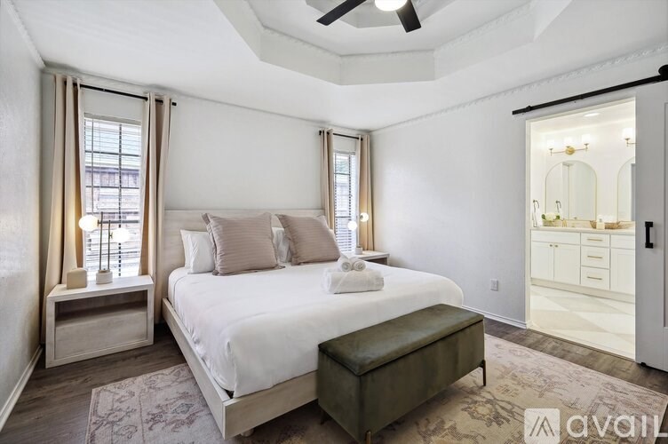 A bedroom with a large bed, a bench, and a ceiling fan.