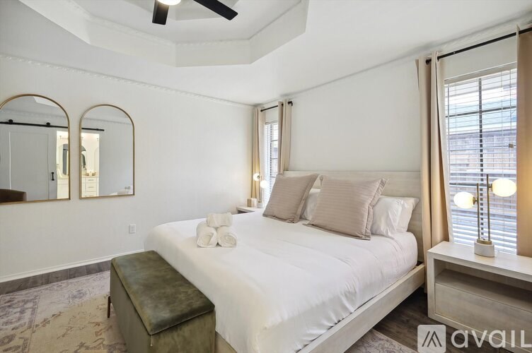 A bedroom with a large bed, a mirror, and a window with curtains.