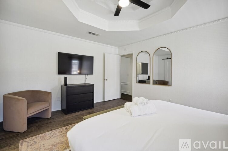 A bedroom with a bed, chair, and mirror.